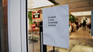 Coronavirus Covid-19 sign in clothing shop window during lockdown saying closed until further notice, showing clothes shops shut in London on a shopping high street in the pandemic in England, Europe