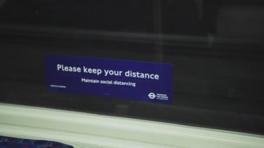 Covid-19 Coronavirus information sign in London Underground tube train carriage for social distancing on public transport in England, UK