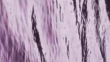 Vertical background video of flowing water, a nature abstract with purple ripples and copy space