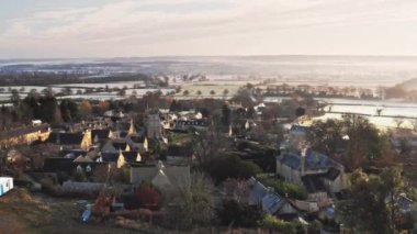 Aerial drone video of a Cotswolds Village, English countryside fields and scenery with houses, property and real estate in the UK housing market, Bourton on the Hill, Gloucestershire, England