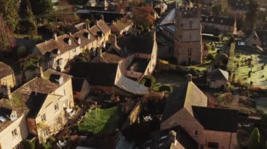 Aerial drone video of a Cotswolds Village Church, a rural scene in English countryside with houses, property and real estate in the UK housing market, Bourton on the Hill, Gloucestershire, England