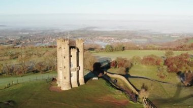 Aerial drone video of Broadway Tower, a famous old building landmark in The Cotswolds Hills, iconic English tourist attraction in beautiful British countryside with green fields, Gloucestershire, England, UK