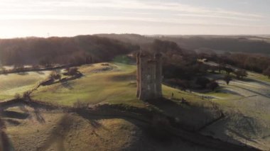 Aerial drone video of Broadway Tower, a famous old building landmark in The Cotswolds Hills, iconic English tourist attraction in beautiful British countryside with green fields, Gloucestershire, England, UK