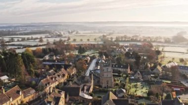 Aerial drone video of a quiet empty roads during Coronavirus Covid 19 pandemic lockdown in a Cotswolds Village in England, English rural scene with countryside and fields, Gloucestershire