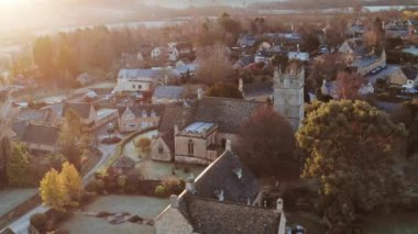 Aerial drone video of Typical English village and beautiful British countryside scenery in The Cotswolds showing a rural church at sunrise in morning sunlight at Longborough, Gloucestershire, England, UK