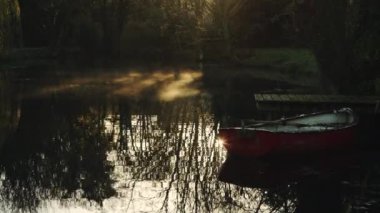 Rowing boat at a pier with mist moving on a lake in a magical peaceful calm atmospheric countryside scene in a beautiful garden, English countryside scene of lakes and trees, England