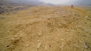 Man running down Illiniza volcanic mountainside, on a foggy and moody day, Ecuador