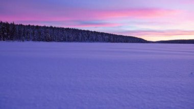 Landscape view of a snow capped forest and lake, in Lapland, Finland, at dusk
