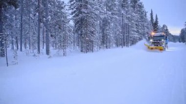 Plowing the snow off the country road in Lapland, Finland - wide shot of plowing
