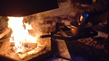 Pouring liquid into a pot over an outdoor fireplace, in Lapland, Finland