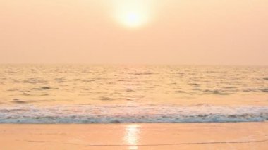 The beautiful colors of sunset over the waves of Goa, India - wide shot