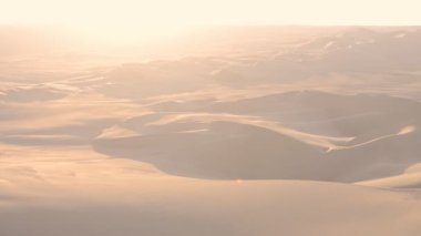 Peruvian desert landscape view with quad speeding on distant dunes, at sunset