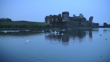View of Caerphilly Castle, Wales, with brids flying on the lake, in the evening