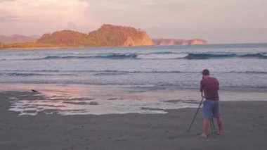 Landscape photographer taking photo of Playa Buena Vista Beach at sunset, Costa Rica. Aerial drone view