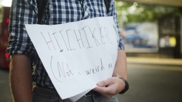 Hitchhiker Holds Sign Asking Rides Side Street Cars Busses Passing — Stockvideo
