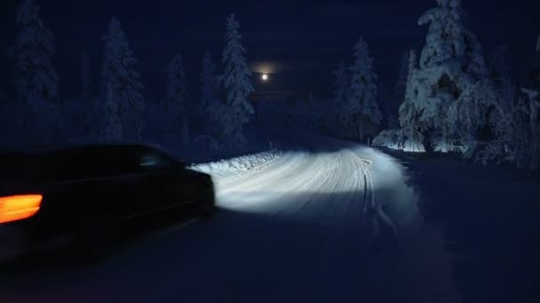 Car Speeding Snowy Road Surrounded Snow Capped Forest Night Moonlight — ストック動画