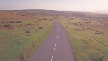 Car driving through Dartmoor National Park, Devon, England, UK. Aerial drone high follow