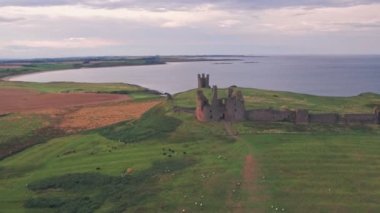 Dunstanburgh Castle at sunset, a famous landmark in Northumberland, England, UK. Aerial drone view