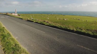 Old car speeding on a country road, Dorset, England, with green fields and the sea in the background
