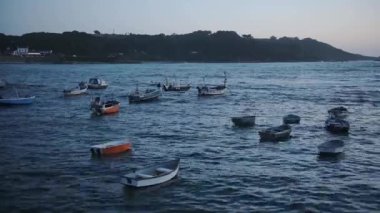 Empty boats tied by the shoreline of Guernsey during the night - wide shot