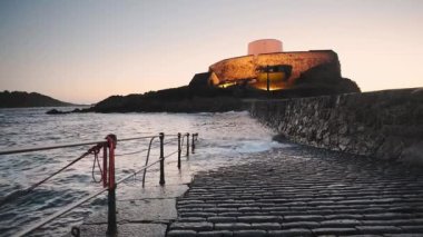 Coastline view and Fort Grey illuminated, Guernsey, at dusk