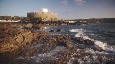 Landscape view of Fort Grey, Guernsey, with sea waves crashing on the rocky coastline