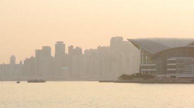 Bright Sunset In Victoria Harbour With Star Ferry Boat Cruising On The Water. Hong Kong Convention And Exhibition Centre.- wide shot