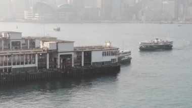 Star Ferry Boat Leaving And Arriving At The Tsim Sha Tsu Pier In Victoria Harbour Hong Kong, China.- wide shot