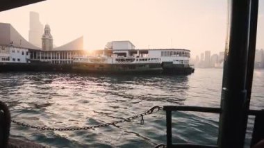 Star Ferry Pier At Tsim Sha Tsui With Clock Tower And Bright Sunset On The Background In Hong Kong. - wide shot