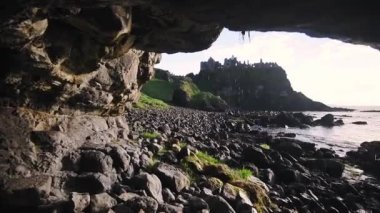 Landscape view from inside a cave of Dunluce Castle, Northern Ireland, on a sunny evening