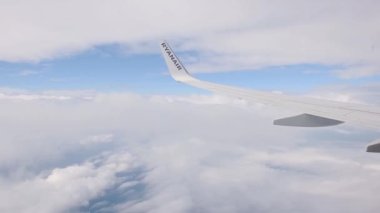 On an airplane soaring through the clouds on a bright sunny day - wide shot