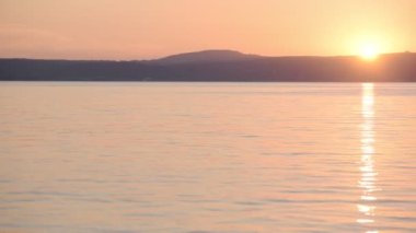The Beautiful View Of A Deep Calm Ocean And Mountains In Italy With A Red Orange Sky During Sunset - Wide Shot