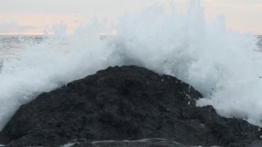 Seascape view of ocean waves crashing on the rocky shore, in Watamu Beach, Kenya, at dusk