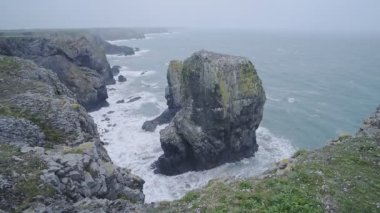 Waves crashing on the cliffy coastline and on Elegug Stacks, Pembrokeshire Coast National Park, Wales