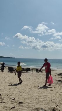 Bali, Endonezya - 15 Mart 2022: Dikey Ekran: Jimbaran sahilinde güzel gökyüzü, Bali. Deniz kenarındaki restoran koltukları kuruluyor..