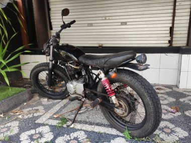 Bali, Endonezya - 15 Mart 2022: Eski okul motosikleti kapalı bir dükkanın önünde park edilmiş.