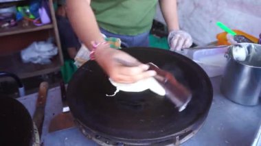 white woman hand makes a crepe pancake on a baking tray in a creperie. sale at street food
