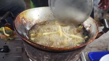 French fries are fried in a large pot. Potatoes Fried in oil. Street food festival.