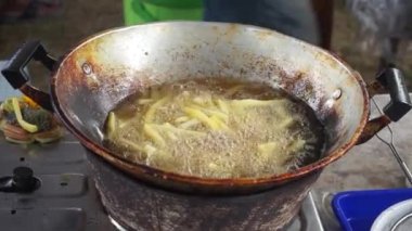 French fries are fried in a large pot. Potatoes Fried in oil. Street food festival.
