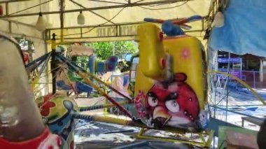 Bali, Indonesia - July 10, 2022: A little boy rides a carousel on an amusement ride. The kid rides on an airplane in the playground.