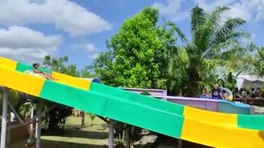 Badung, Bali, Indonesia - July 9, 2022: Visitors play in the outdoor water park featuring a swimming pool and waterslide, attractions for large and small.