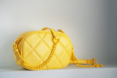 Yellow cross body quilted bag. Ladies bright-colored handbag on gray background. Yellow woman bag.