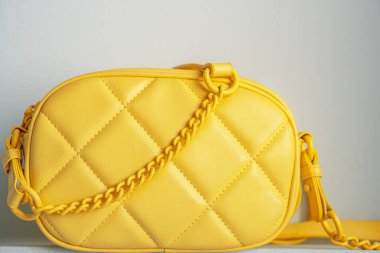 Yellow cross body quilted bag. Ladies bright-colored handbag on gray background. Yellow woman bag.