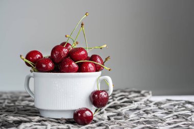 Ripe organic cherries on gray background with copy space. Water drops on ripe juicy cherries