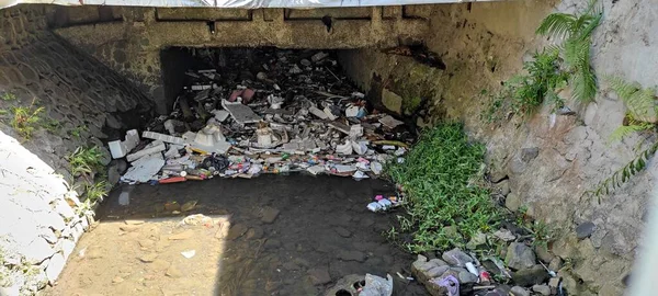 Heaps of garbage, which clog the river waterways, under the bridge.