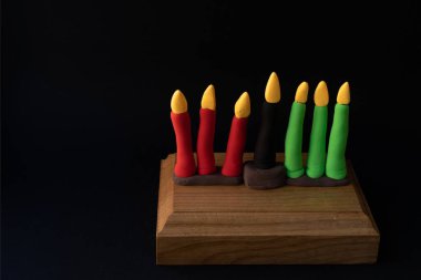Kinara. Traditional Kwanzaa symbols. Isolated on black background. African American holiday. Hand-sculpted kinara from plasticine