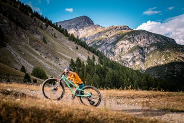 Aktif çocuk bisikletini yukarı itiyor. Dağ bisikletli küçük bir binici. Enduro dağlarda at sürüyor..