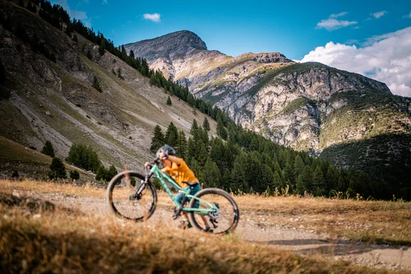 Aktif çocuk bisikletini yukarı itiyor. Dağ bisikletli küçük bir binici. Enduro dağlarda at sürüyor..