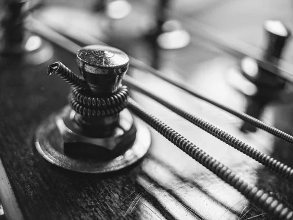 Bir akustik gitarın akort tuşlarının siyah ve beyaz olarak yakın plan görüntüsü.
