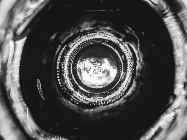 Looking down into a glass bottle with light behind in black and white.